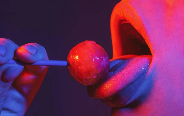 Lollipop i kvinnans mun, rött läppstift. Kvinnan slickar en röd skinande klubba. Närbild. Sexig kvinna med klubba i sexig mun på neonljus. Nattklubb bakgrund — Stockfoto