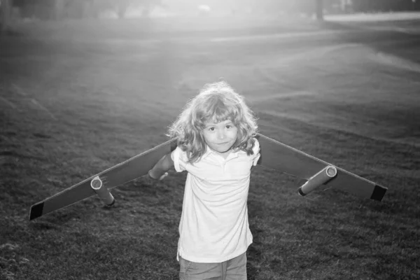 日没の芝生のフィールドでおもちゃのジェットパックで遊んでいる子供。子供のパイロット宇宙飛行士や宇宙飛行士の夢。ボールボードの翼を持つ飛行士の少年. — ストック写真