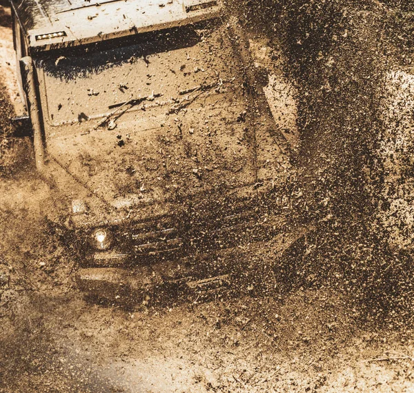 Offroad voertuig coming out van een gevaar voor het gat van modder. Safari suv. Off-road rijden op een bergweg. Tracks op een modderige veld. Mudding is uitgeschakeld-achteruitgaat door een gebied van natte modder of klei. — Stockfoto