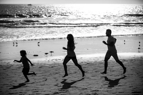 Silhuetter av fitness familj kör nära havet. — Stockfoto