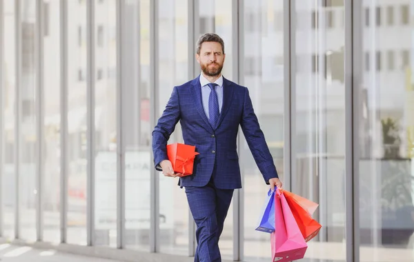 Hombre de negocios llevando bolsas de compras, caminando en la ciudad. —  Fotos de Stock