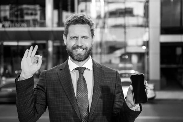 Бизнесмен с телефоном. Портрет веселого офисного работника, разговаривающего по мобильному телефону рядом с современным офисом. — стоковое фото