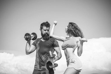 Açık havada halterli, sportif bir çift. Dambıllarla çalışan bir çift. Gökyüzündeki spor salonu..