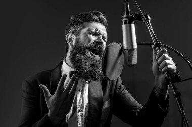 Kayıt stüdyosunda şarkı söyleyen adam. Mikrofonlu etkileyici sakallı adam. Karaoke imzacısı, müzik vokalisti.