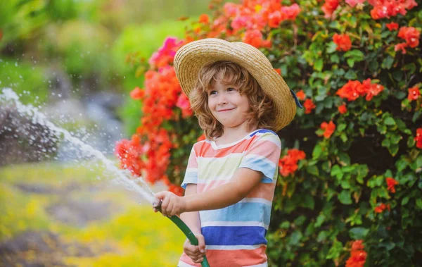 Καλά να περάσεις. Αστείο αγόρι χαρούμενο χαμογελαστό στο φυσικό τοπίο. Το μικρό παιδί διασκεδάζει στον καθαρό αέρα. Το να είμαι αστείος είναι μια από τις μεγαλύτερες δυνάμεις μου. Πότισμα φυτών στον κήπο στο σπίτι την ηλιόλουστη μέρα του καλοκαιριού. — Φωτογραφία Αρχείου