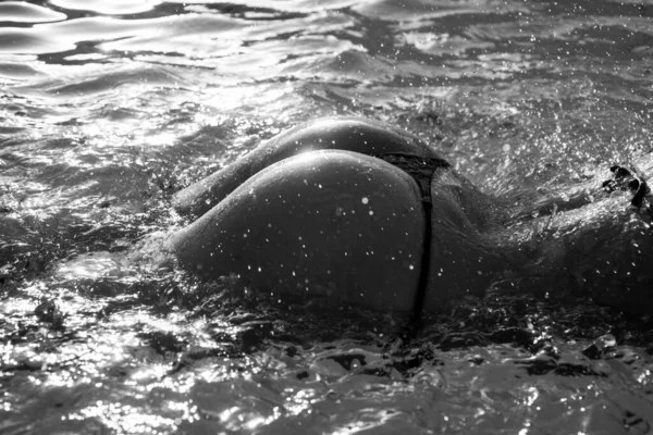 Bikinili kadın poposu. Yaz tatilleri. Sıska ve zinde bir kızın vücut parçası deniz suyunun üstünde.. — Stok fotoğraf