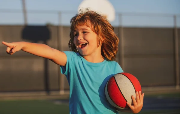 Szczęśliwy uśmiechnięty dzieciak grający w koszykówkę, pokazujący gest. Aktywność i sport dla dzieci. — Zdjęcie stockowe