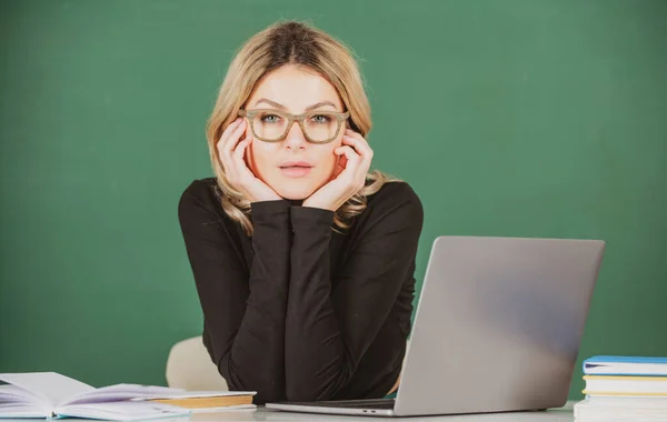 Profesora atractiva y concentrada. Retrato de una joven inteligente en gafas con libro en la pizarra en clase en la escuela secundaria o collage. Estudiante femenina en la universidad. —  Fotos de Stock