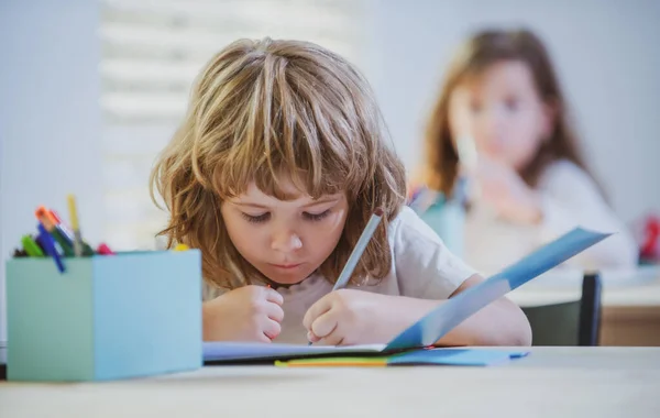 A srác tanul az iskolában. Iskolásgyerek házi feladatot csinál az osztályteremben. Oktatás gyerekeknek. — Stock Fotó