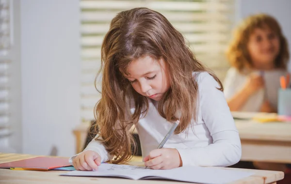 Eğitim, öğrenme ve çocuk kavramı. Kitap yazma sınavı olan küçük bir öğrenci. Okula dönelim. Mutlu şirin çocuk içeride bir masada oturuyor. Çocuk sınıfta öğreniyor.. — Stok fotoğraf