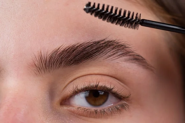 Womans eyebrows. Beautiful girl with eyebrow brush. Girl with natural make up. Eyebrow correction. Macro close up of brows. Microblading, modeling brows. — Stock Photo, Image