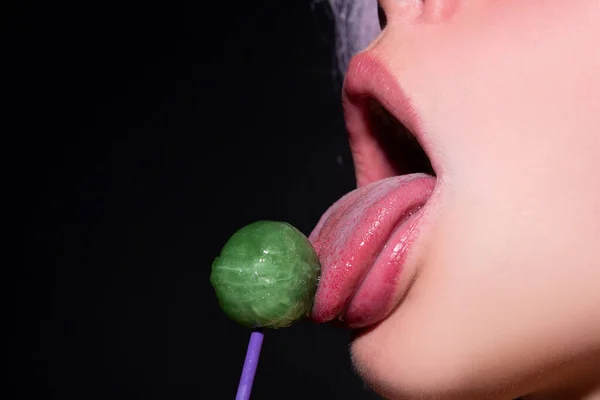 Cukorkát nyalni. Nyalóka modell. A nő szája cukorkát szív. Glamor szexi modell piros ajkak enni izzadság nyalóka pop. — Stock Fotó