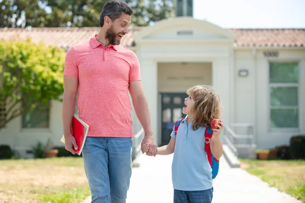 Père et fils vont à l'école, à l'éducation et à l'apprentissage. Parent et élève de l'école primaire écolier avec sac à dos. — Photo