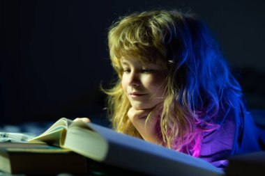 Çocuk masal okuyor, karanlık oda fotoğrafı. Çocuk kitap okuyor. Çocuklar yatma vakti, çocuk yatakta kitap okuyor..