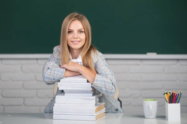 Retrato de uma jovem, confiante e atraente estudante estudando na sala de aula da escola. Estudante bonito menina com livros no fundo do quadro negro com espaço de cópia. — Fotografia de Stock