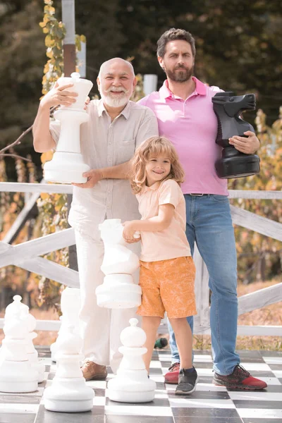 Großvater Vater und Sohn beim Schachspielen. Männer in verschiedenen Altersgruppen beim Schachbrettspiel. Wochenend-Familie. Vatertagskonzept. — Stockfoto