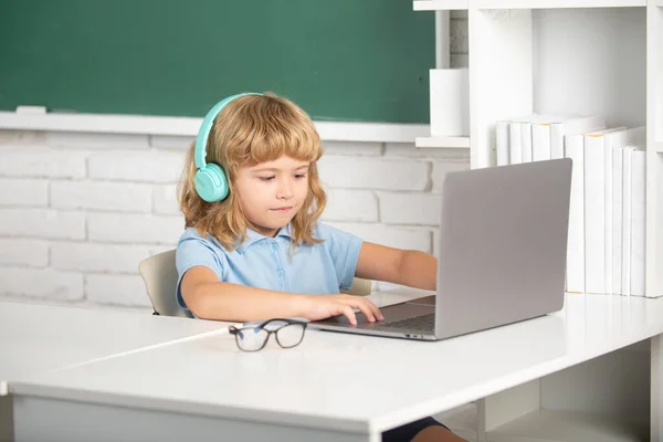 Programação de crianças genial. Menino em fones de ouvido usando um laptop e estudar on-line com professor de chamadas de vídeo na escola. — Fotografia de Stock