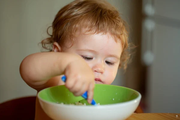 家族、食べ物、子供、食事、親の概念。幸せな赤ん坊はスプーンで自分自身を食べる. — ストック写真