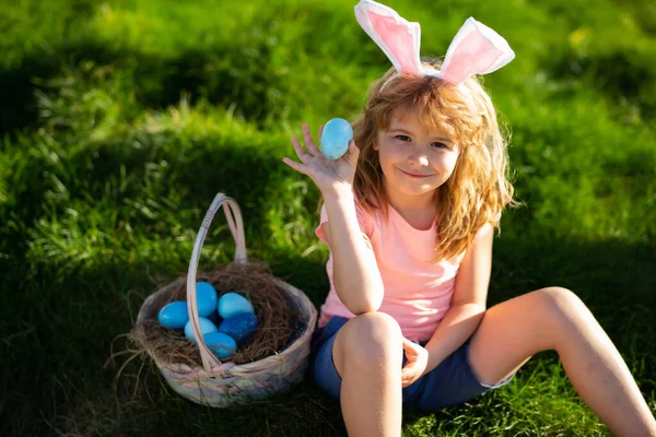 Caça aos ovos da Páscoa. Feliz Páscoa. Crianças em orelhas de coelho com ovo de Páscoa na cesta. Menino jogar em ovos de caça. — Fotografia de Stock