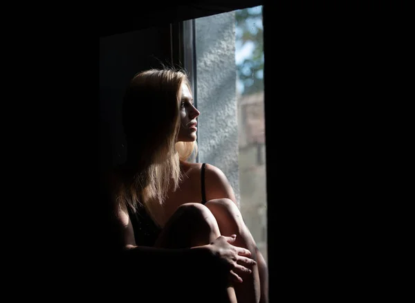 Chica sensual cerca de la ventana. Mujer en la sombra. Modelo femenino con sombras en cara seductora y sensual en dramático estudio negro con luz. — Foto de Stock