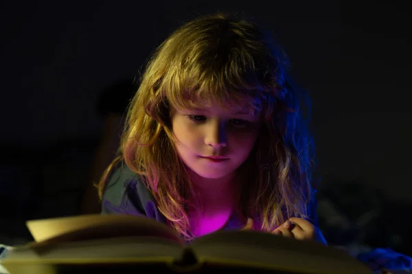 Criança a ler um livro de magia na cama. O miúdo leu livros em casa. Desenvolvimento infantil da imaginação. — Fotografia de Stock