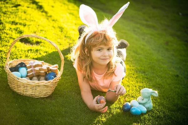 Kind met paaseieren en konijnenoren op gras. Grappige jongen, paashaas kinderen. Gelukkige Pasen kinderen gezicht. — Stockfoto