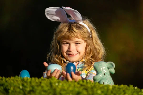 Feliz día de Pascua. Niños con orejas de conejo celebrando la Pascua. Niño cazando huevos de Pascua en el patio trasero. Retrato de cerca de niños lindos. —  Fotos de Stock