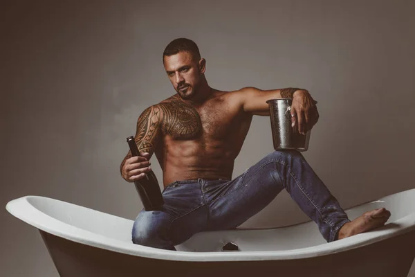Homme sexy sur baignoire avec champagne. Célébration de Noël ou d'anniversaire gay. Partie de sexe privé. — Photo