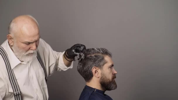 Kapsalon, haarkleurige man. Aantrekkelijke senior kapper doet een kapsel en haarkleur voor klant bij kapper. Senioren kapper drogen haar. — Stockvideo