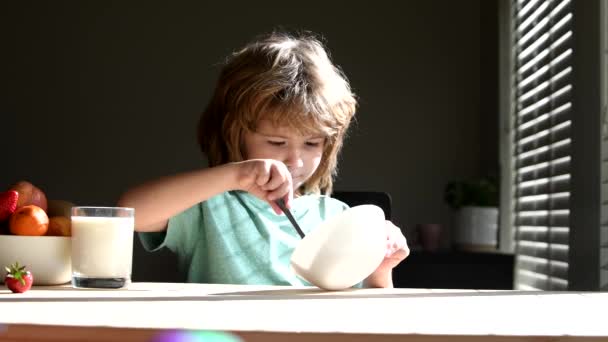 Діти їдять кашу та молоко на ранковий сніданок. Діти їдять і п'ють. Маленький хлопчик з великими пальцями вгору сніданок на кухні . — стокове відео