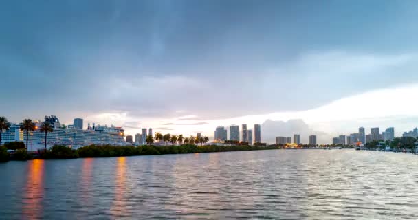 Miami panoráma időeltolódás. Naplemente az égbolton és felhők mozognak a víz hullámos visszaverődésével. Éjszakai égbolt idő Miami Beach City-ben. A város nappali és éjszakai járása. — Stock videók