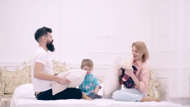 Madre padre e hijo hijo juegan en la cama. Familia feliz teniendo pelea de almohadas en el dormitorio. — Vídeos de Stock