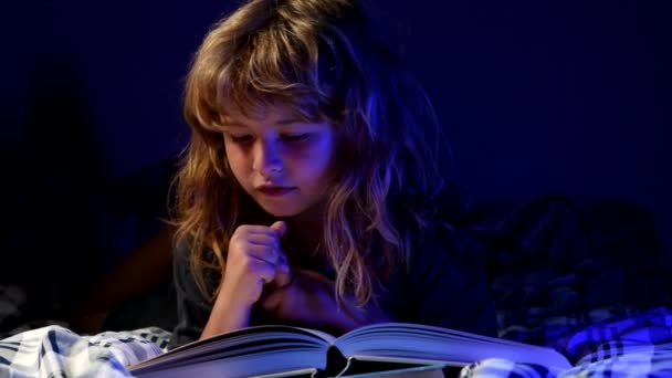 Criança a ler livros. Está na hora de dormir. Menino lendo um livro na cama. — Vídeo de Stock