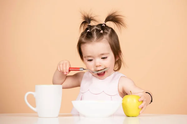 Schattig baby kind eet voedsel, baby 's eten. Kind eet gezond voedsel met een lepel in de studio, geïsoleerd. Grappige kinderen gezicht. — Stockfoto