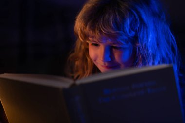 Çocuk kitaptan masal okuyor. Kitap okuyan şirin bir çocuk. Açık kitabı olan bir çocuk. Ev okulu dersi. Evde kitap okuyan konsantre küçük çocuk..