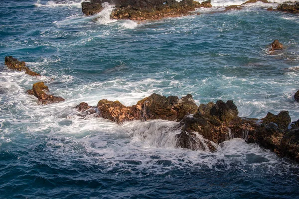 Mořská kamenitá pláž, mořské vlny. Barevné modré moře pozadí. Koncept letní dovolené a cestování. Čistá mořská voda, velké kameny na pláži. — Stock fotografie