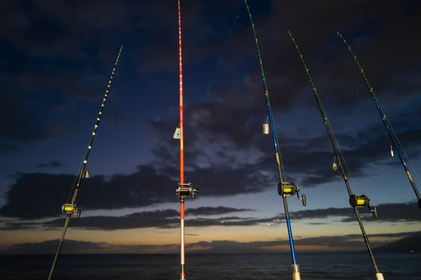 Caña de pescar contra el océano o el mar al atardecer. Cañas de pescar instaladas en la playa al amanecer. — Foto de Stock
