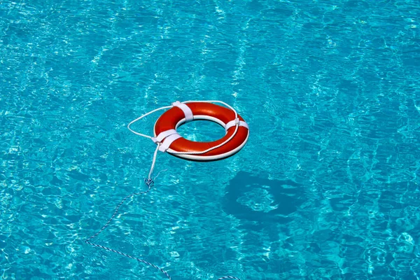 蓝色游泳池里的救生圈救生圈漂浮在蓝色的水面上. — 图库照片