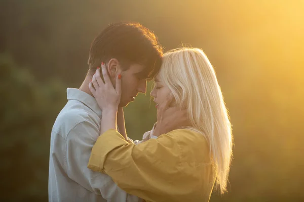 Sensuele minnaars knuffelen en zoenen bij zonsondergang. Sensueel portret van verliefd jong stel. Liefdevol koppel omarmen en kussen. — Stockfoto