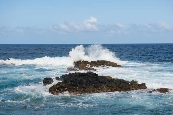 Fala uderzyła w skałę na plaży, woda morska rozprysła się na morzu. Przylądek morski. Rozpryski fal uderzające o skalisty brzeg. — Zdjęcie stockowe