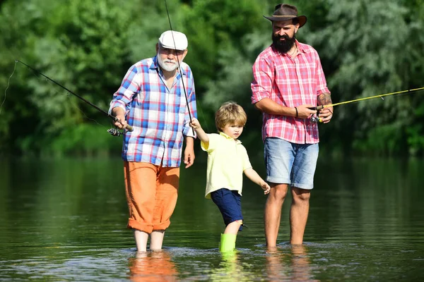父亲、儿子和祖父都在钓鱼。年轻人-成年人的概念.14.业余活动和体育活动。爷爷和孙子孙女在河里玩得很开心. — 图库照片