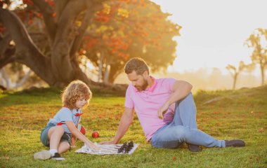 Çocuk satranç okulu. Baba ve oğul dışarıda satranç oynuyorlar..