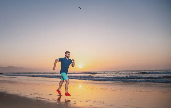 Coureur sur la plage courir pour l'exercice. Coureur actif en bonne santé faisant du jogging extérieur. Jeune homme s'entraînant sur la plage le matin. — Photo