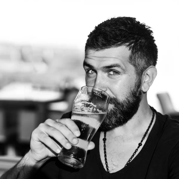 Brutální hipsterský vousáč sedí u baru. Hipster odpočívá v hospodě. Muž drží sklenici piva. — Stock fotografie
