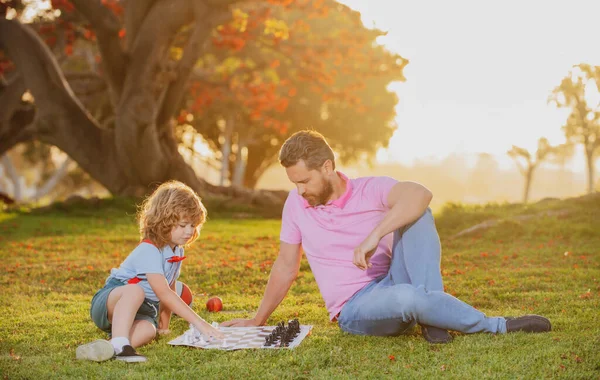 Çocuk satranç okulu. Baba ve oğul dışarıda satranç oynuyorlar..