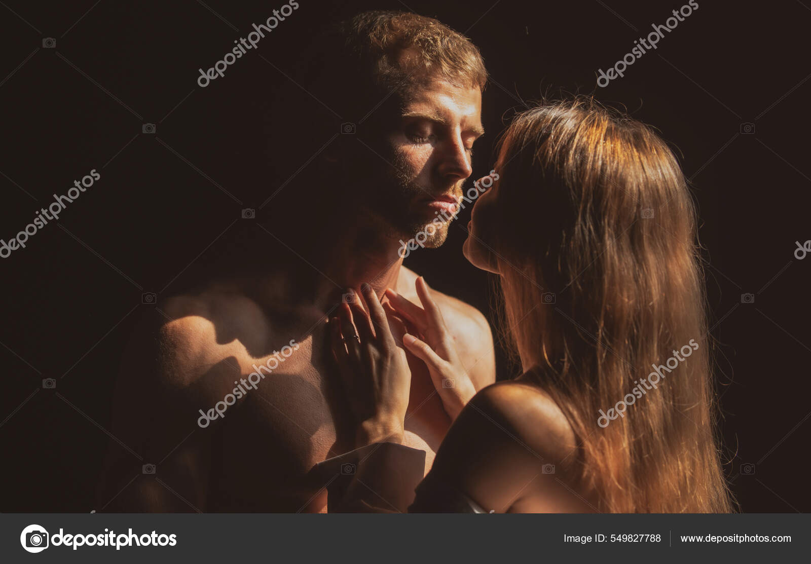 Portrait of lovely couple in love. Young sensual girlfriend glad to passionate kiss from her boyfriend. Handsome man embraces his woman and kisses picture