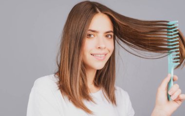 Saçlarını tarayan gülümseyen bir kadın. Güzel bir kız uzun saçlarını tarıyor..