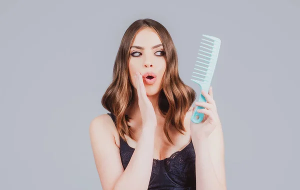 Surprised woman hairdresser with comb brushing hair. — Stock Photo, Image