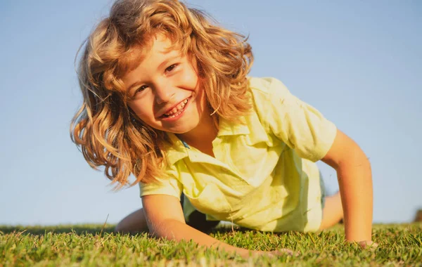 Retratos de niños felices jugando y tumbados en la hierba al aire libre en el parque de verano. —  Fotos de Stock