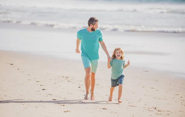 童年和养育子女的概念。父亲和儿子在夏天的海滩上奔跑. — 图库照片